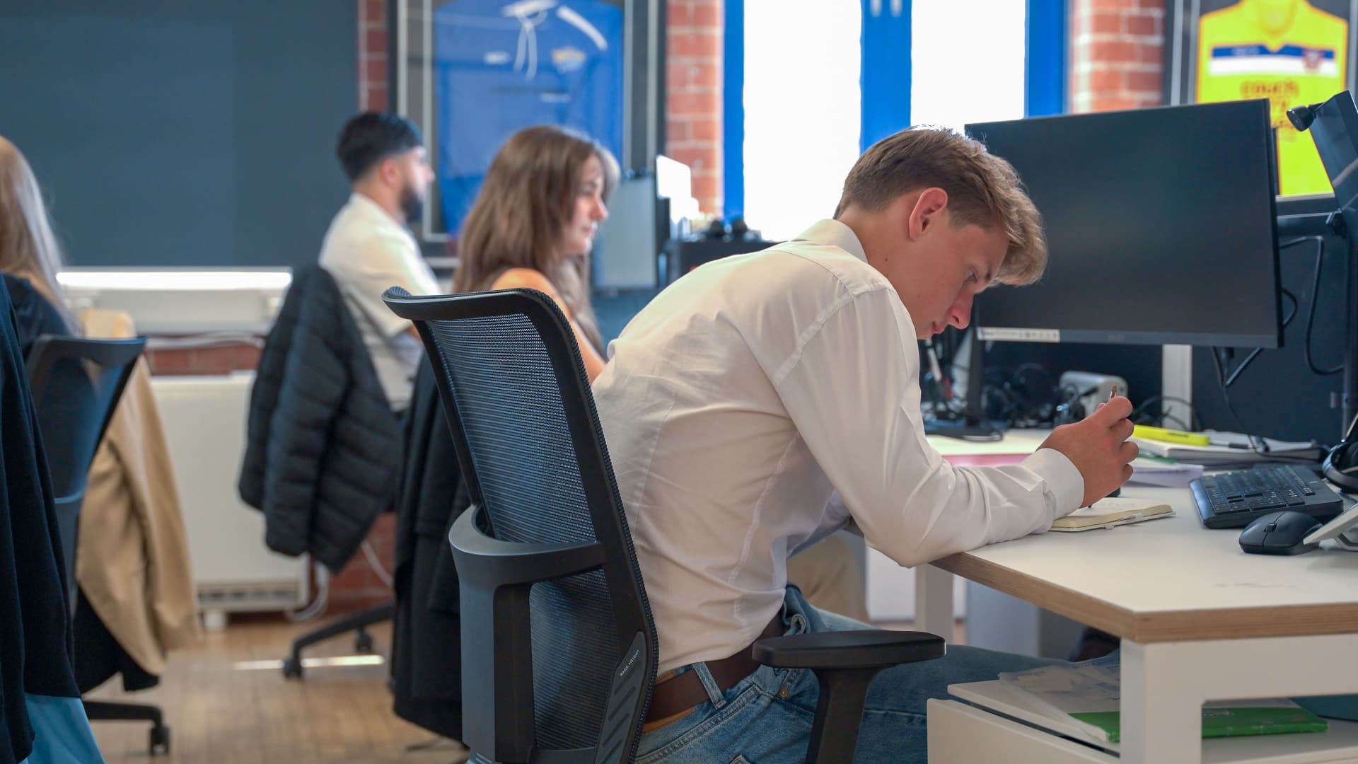 A CPW engineer working at a desk in a busy open-plan office